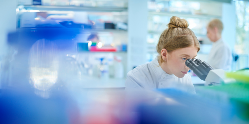 Scientist looks into microscope in a clinic setting